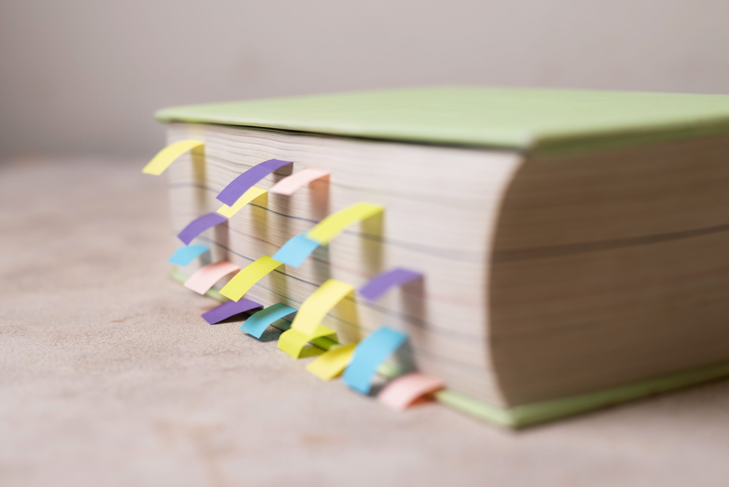 Libro grueso con numerosas cintas adhesivas de colores utilizadas como marcadores de estudio.